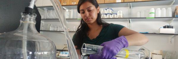 Nisha pours liquid into a funnel in laboratory